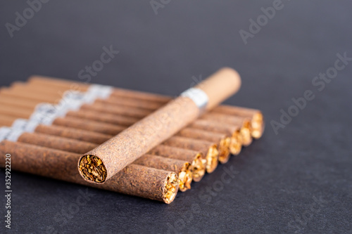 фотографія brown cigarettes with a filter on a background of black textured paper