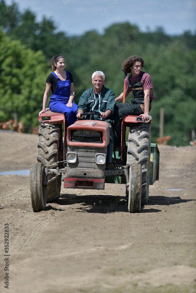 Farmer with apprentice riding tractor in farmland