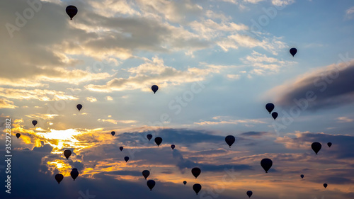 Many passenger balloons fly against the background of dawn in the clouds