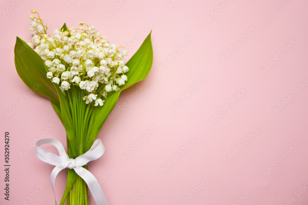 Lily of the valley flowers. Bouquet of Lily of the valley flowers on pink background. Flat lay, top view, copy space.