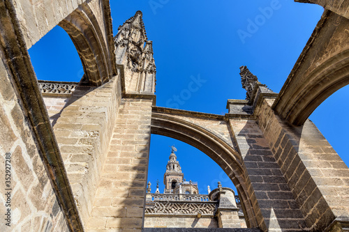 Roof of Seville Cathedral - A close-up low-angle view of the pinnacles and flying buttresses on the roof of Seville Cathedral, with top of La Giralda tower in background. Seville, Andalusia, Spain.