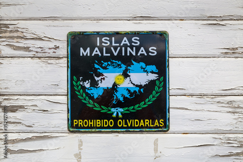 Sign plate with 'Islas Malvinas - forbidden to forget' words on old white wooden wall in Ushuaia port, Tierra del Fuego province, Argentina