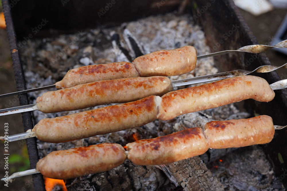 Close up of toasted sausages on skewers. Succulent kupaty roasting on chargrill. Concept of picnic outdoor. Close up of toasted sausages on skewers. Succulent kupaty roasting on chargrill. Concept of picnic outdoor.