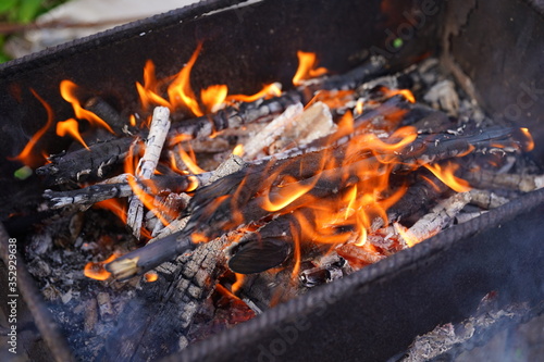 Close up of fire on chargrill. Dry sticks smoulder. Concept of cooking on grill.