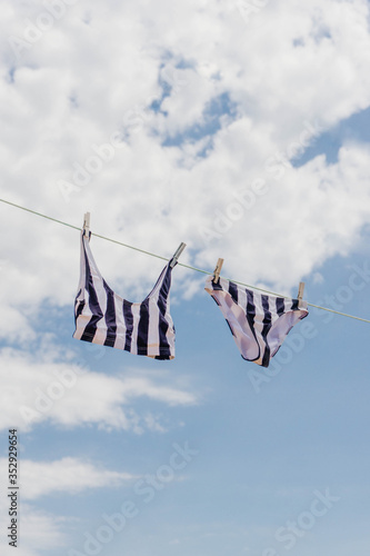 Two pieces swimsuit hanging in a clothes line against blue sky. Summer concept.