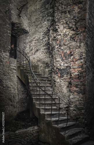 An old medieval circual staircase with an iron metal balustrade leading to an old rustic door in a fortress or cathecdral wall with copy space on the limestone wall photo