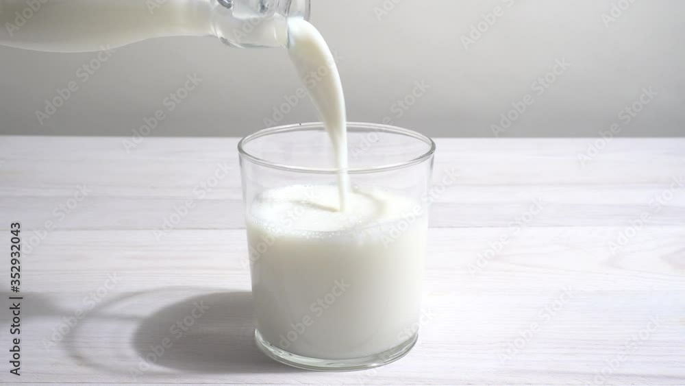 Vertiendo leche en un vaso en la mesa