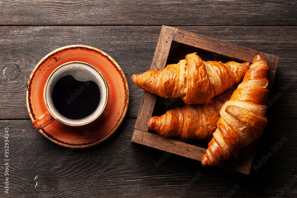 Coffee and croissants on wooden table Coffee and croissants on wooden table