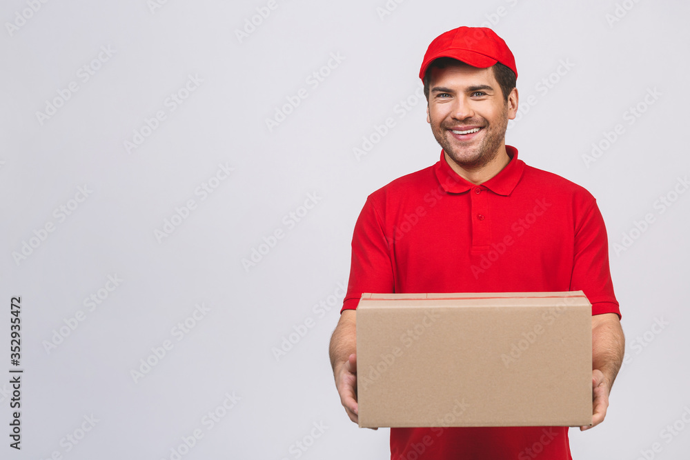 Image of a happy young delivery man in red cap standing with parcel post box isolated over white background. Image of a happy young delivery man in red cap standing with parcel post box isolated over white background.
