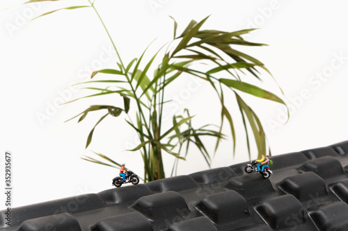 Two motorcyclists ride over a mountain-like piece of exercise equipment with a green plant in the background - Tiny People Adventuring