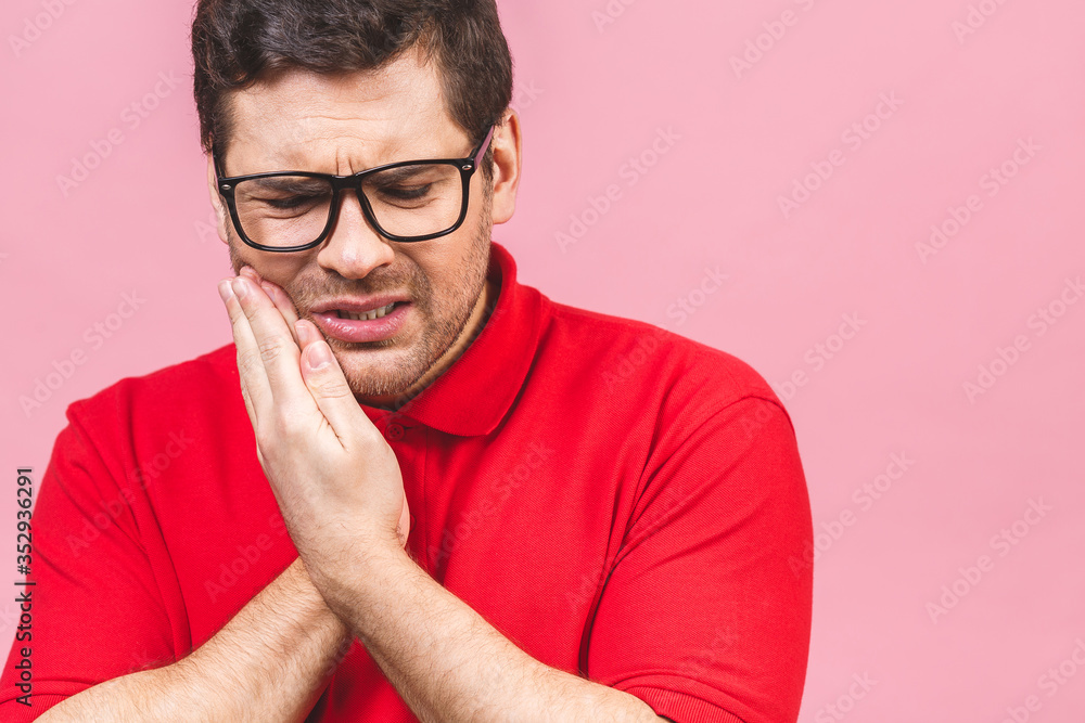 Tooth ache concept. Indoor shot of young male feeling pain, holding his cheek with hand, suffering from bad toothache, painful expression. Tooth ache concept. Indoor shot of young male feeling pain, holding his cheek with hand, suffering from bad toothache, painful expression.