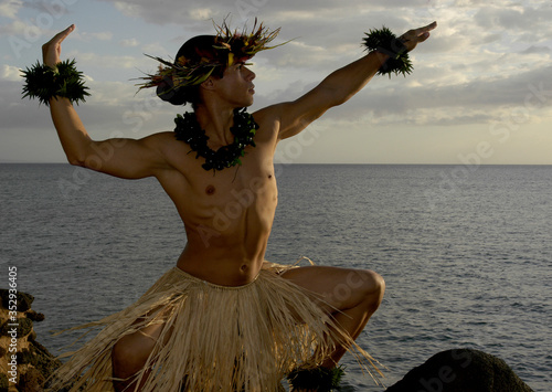 Male Hula Dancer poses on the beach and is almost silhouetted as the sun begins to set.  photo