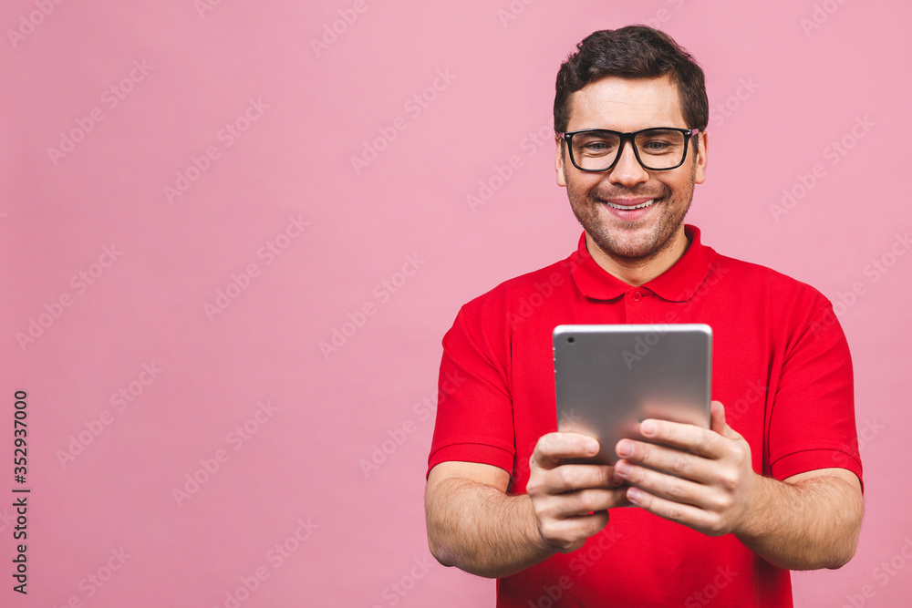 Image of happy young bearded man standing over pink background isolated. Using tablet computer. Image of happy young bearded man standing over pink background isolated. Using tablet computer.