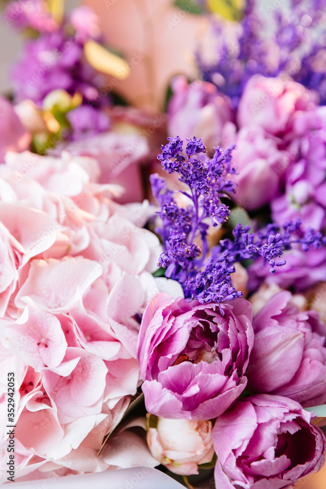 Obraz premium Stylish floral bouquet with pink hydrangea, tulips and roses in pink wrapping paper. Designer flower bouquet from a florist. Beautiful blossoming flower wedding bouquet. Close up