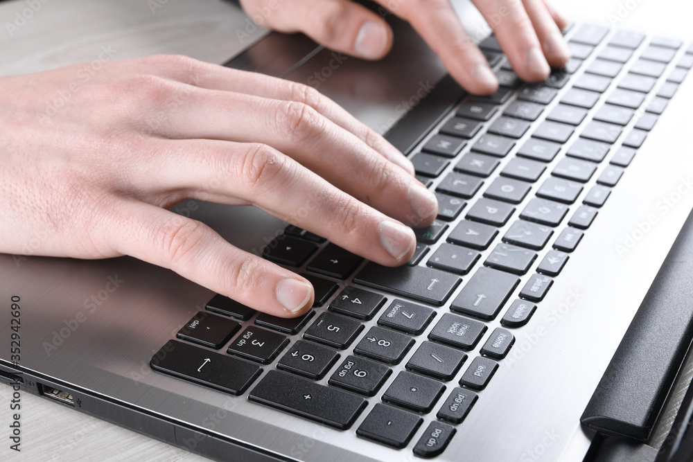 Close-up of typing on laptop keyboard of male hands Close-up of typing on laptop keyboard of male hands