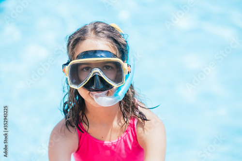 Little girl in the pool with swimming goggles and snorkel