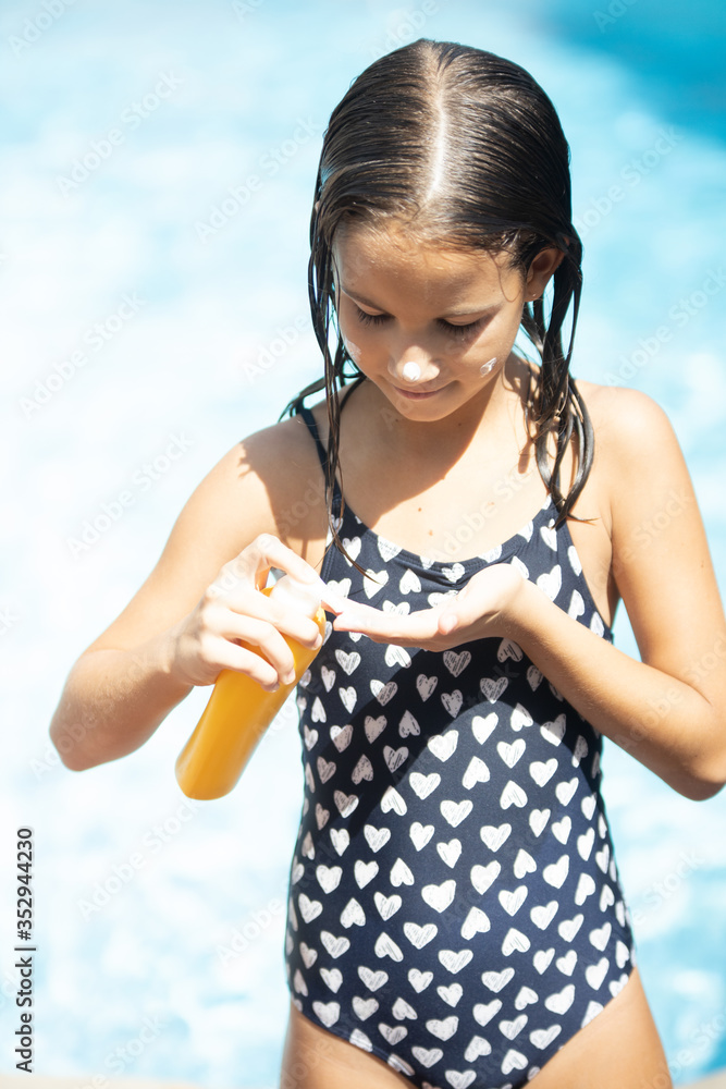 Girl putting suntan lotion on her hand StockFoto Adobe Stock