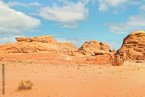 Rocky formations and mountains in sandy desert, blue sky above, typical scenery in Wadi Rum, Jordan