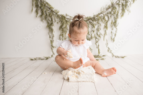 Foto Baby girl first birthday cake smash on a white wood set in a white background an