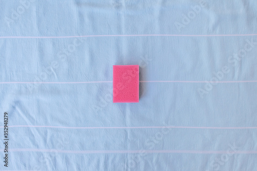 Pink sponge for dishes on a blue background. Card with copy space for text