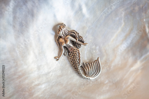 Sterling siver pendant in the shape of mermaid on white shell background