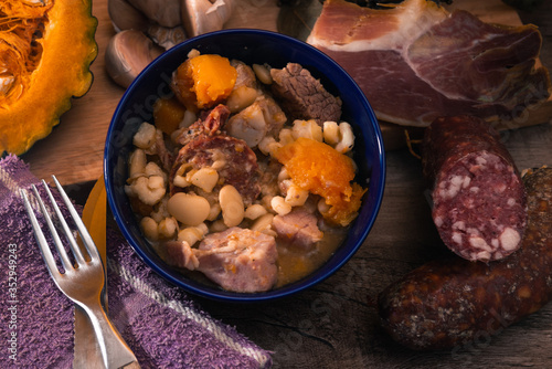 Locro, cocina argentina, un guiso muy popular hecho con calabaza, frijoles, maíz blanco, carne, salchichas, etc. Sobre una tabla de madera photo