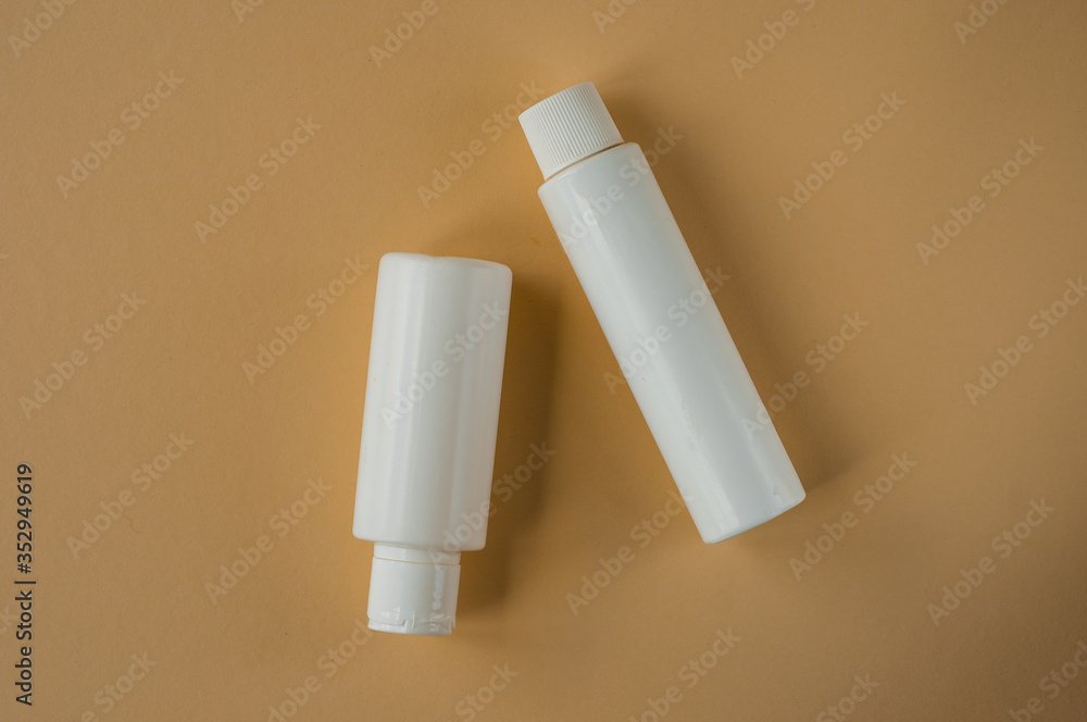Facial and body care cosmetics bottles composition on brown background. Gel tube, lipstick, cream jar unbranded blank packages. Skincare female products advertising with beige backdrop Facial and body care cosmetics bottles composition on brown background. Gel tube, lipstick, cream jar unbranded blank packages. Skincare female products advertising with beige backdrop