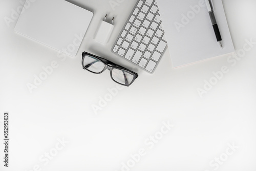 White keyboard, touchpad, pen, notebook, charger and glasses. Freelance. Copy space. Top view.