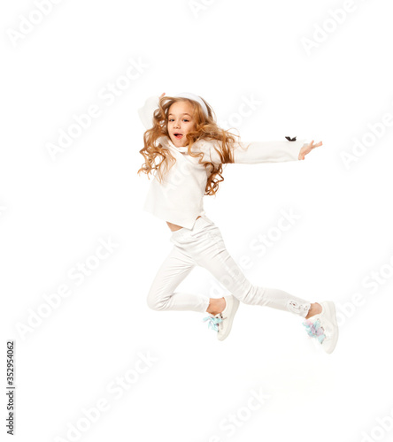 A girl with long hair, dressed in white colored clothes, is jumping on a white background.