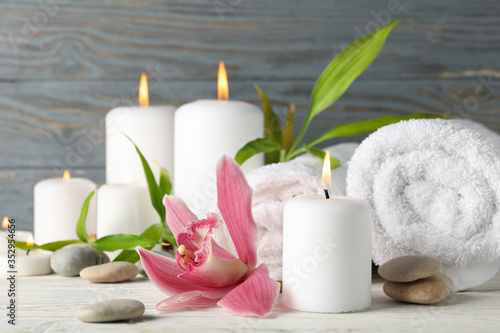Composition with candles, towels, stones and orchid on wooden table. Zen concept