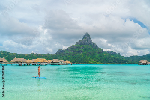 Tahiti beach vacation luxury resort hotel in Bora Bora  French Polynesia. Paddleboarding watersport leisure activity SUP paddle woman  French Polynesia. Mount Otemanu landscape summer holiday.