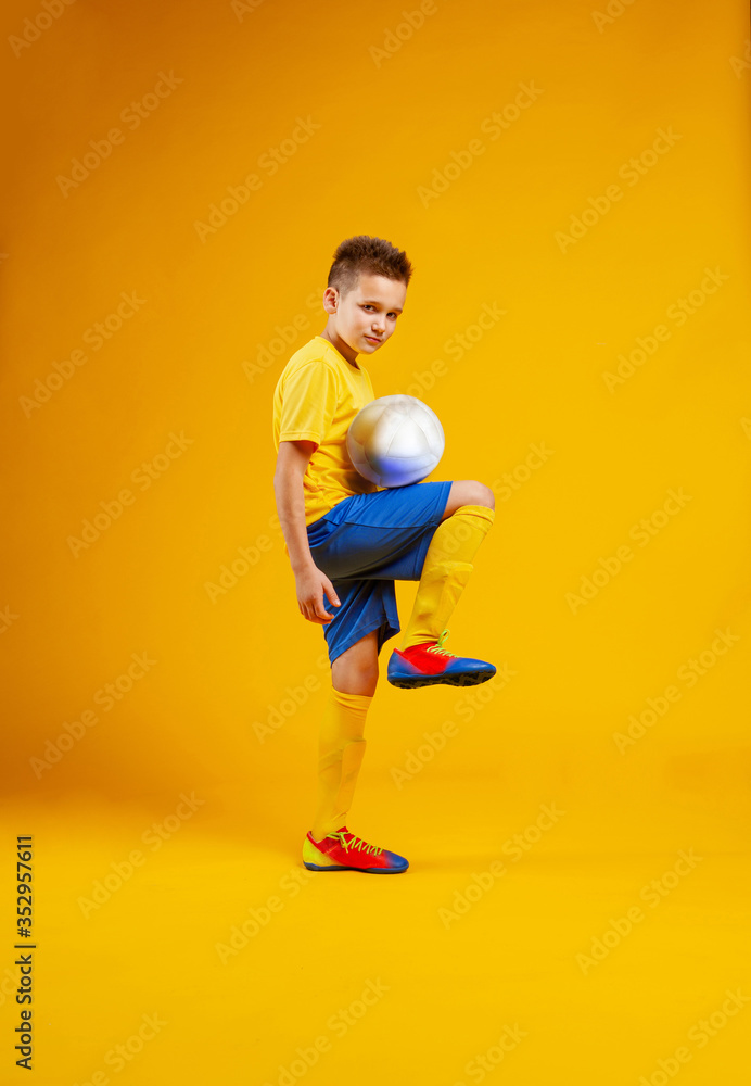 boy plays soccer ball in studio on a yellow background boy plays soccer ball in studio on a yellow background