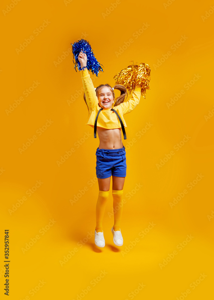 Cute Cheerleader Girl in a Yellow Tank and Blue Shorts Holds Pompons and  Dances / Jumps Stock Image - Image of cheerleading, adorable: 181952739
