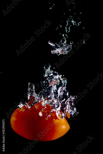 tomato falling in water black background