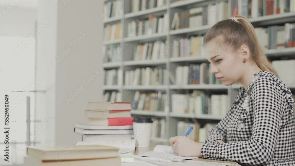 cyoung female student writing in their textbooks at library cyoung female student writing in their textbooks at library