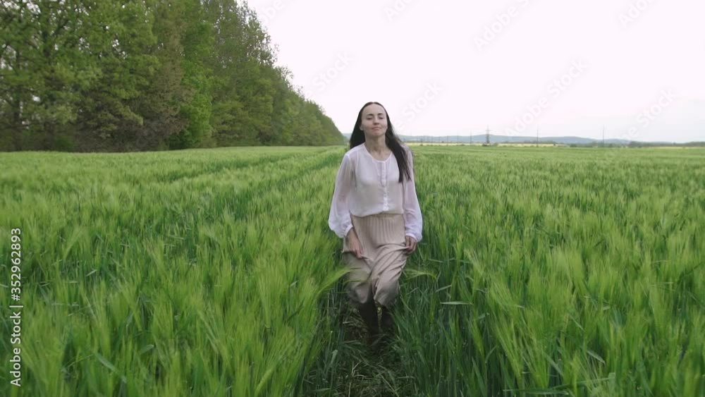 young caucasian girl with black hair in a white shirt and skirt runs across a wheat field at sunset and smiles at the camera and feels happy young caucasian girl with black hair in a white shirt and skirt runs across a wheat field at sunset and smiles at the camera and feels happy