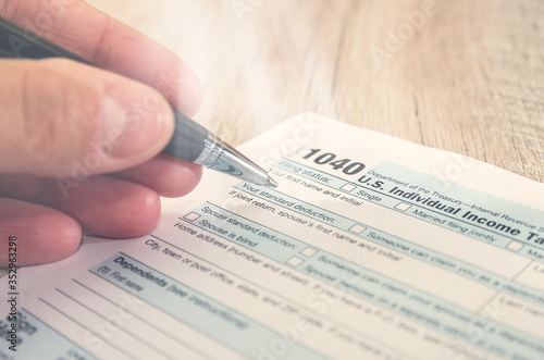 US Individual Income Tax Form with pen. Hand with pen fills tax form 1040. Close-up. photo