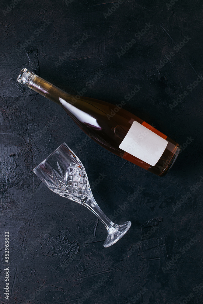 Bottle of rose wine with a glass on black textured isolated background photographed with studio light.