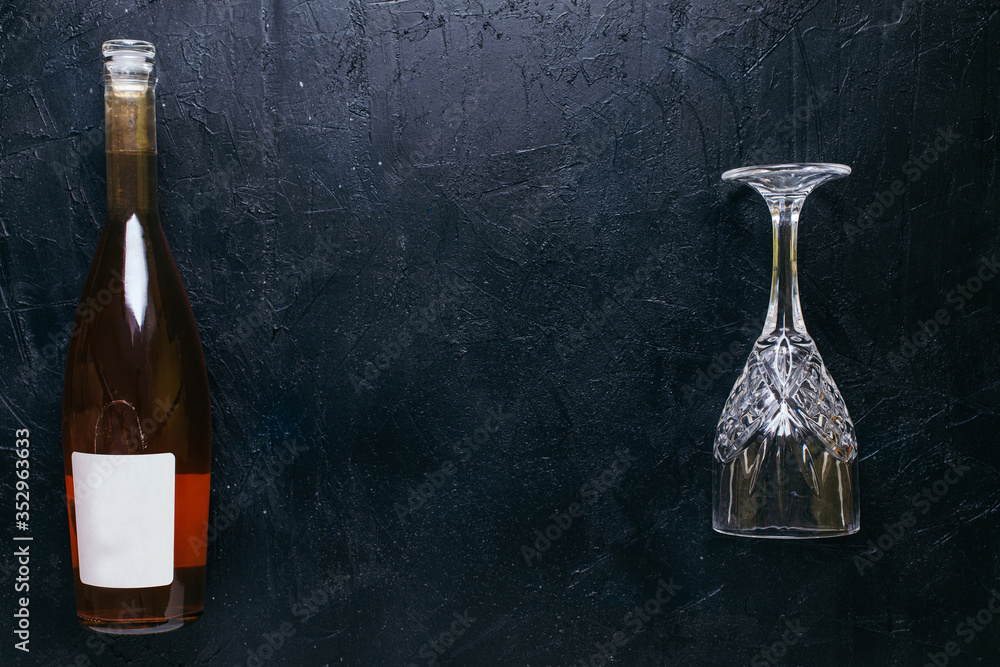 Bottle of rose wine with a glass on black textured isolated background photographed with studio light.