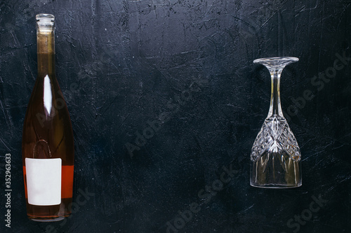 Obraz na płótnie Bottle of rose wine with a glass on black textured isolated background photographed with studio light. w salonie