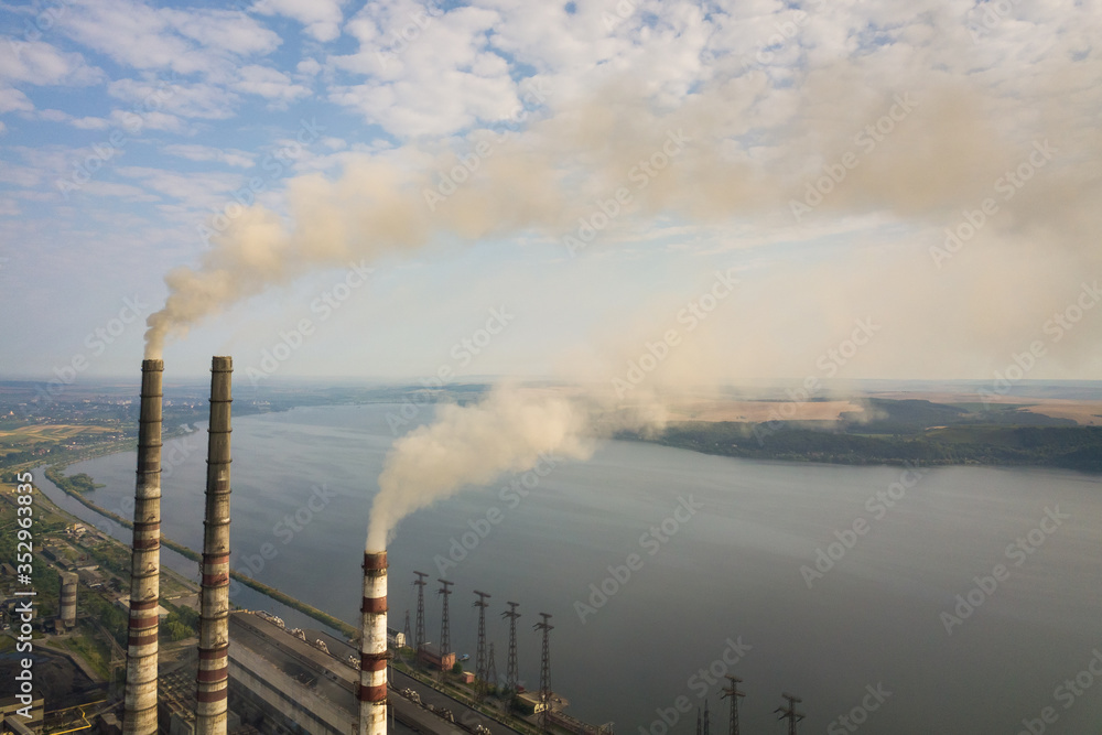 Aerial view of high chimney pipes with grey smoke from coal power plant. Production of electricity with fossil fuel. Aerial view of high chimney pipes with grey smoke from coal power plant. Production of electricity with fossil fuel.