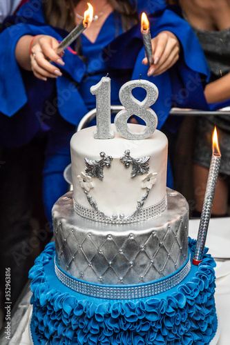 Girl holding firework sticks on the 18 birthday party. Birthday cake with number 18.