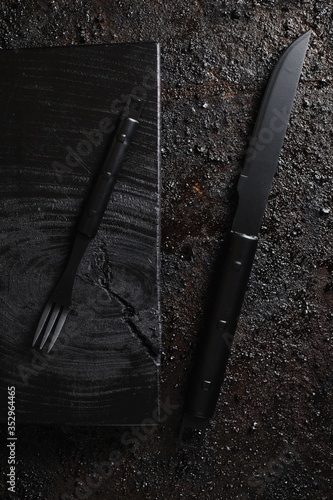 Obraz na płótnie Knife and for on pice of black wood and black texturated background. w salonie