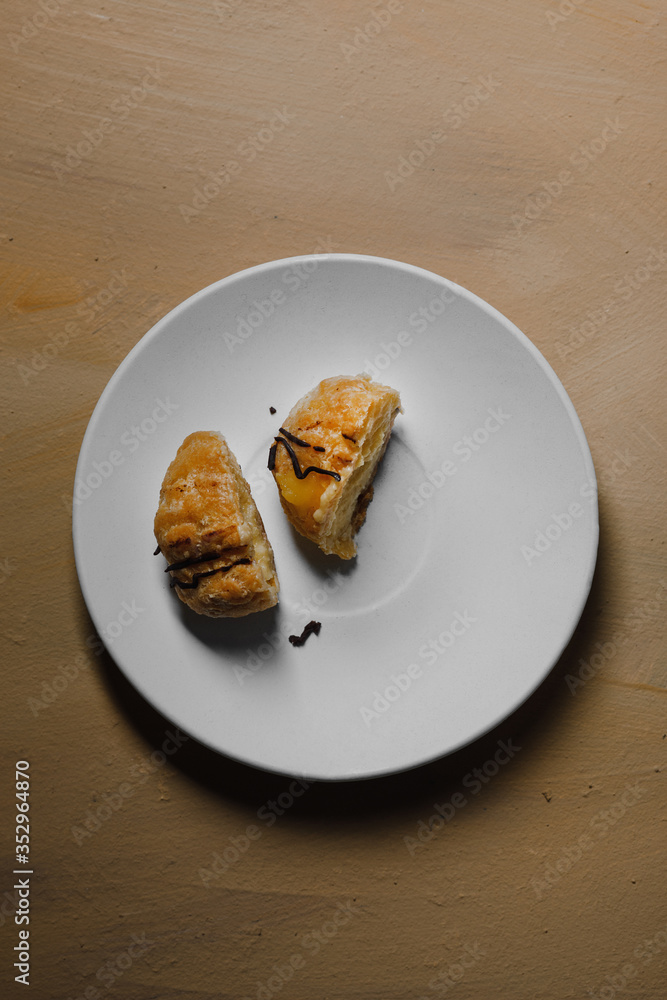 Delicious profiteroles on white mate dish and yellow isolated background.