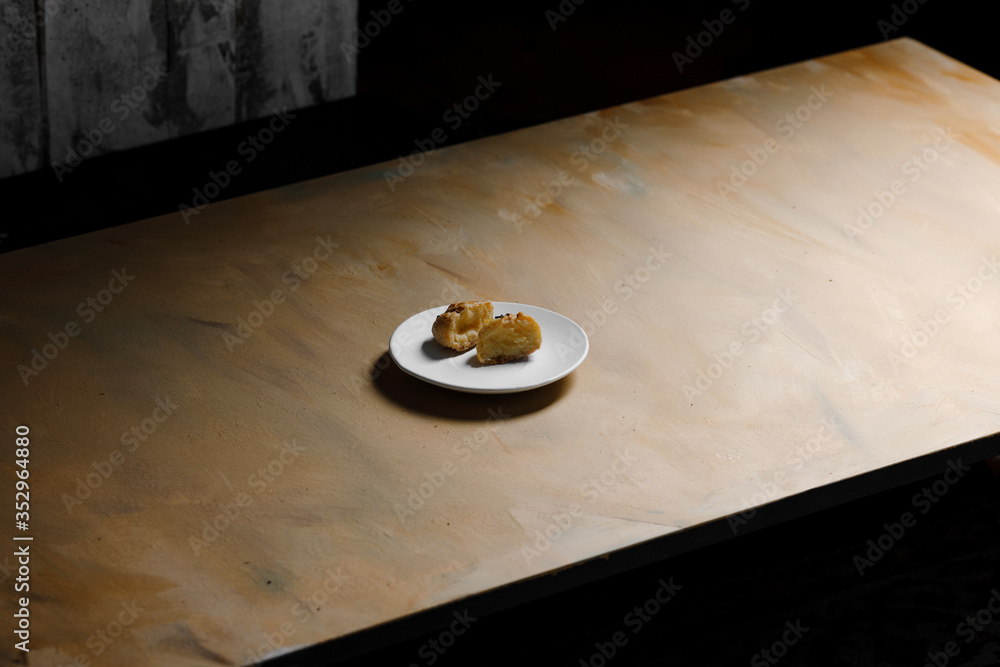Delicious profiteroles on white mate dish and yellow isolated background.