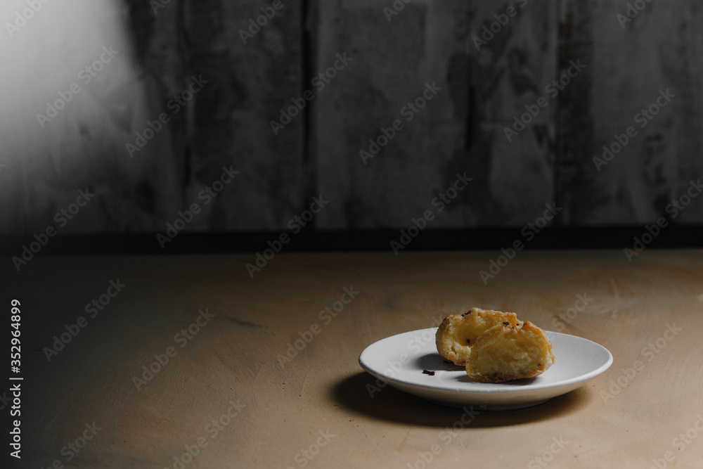 Delicious profiteroles on white mate dish and yellow isolated background.