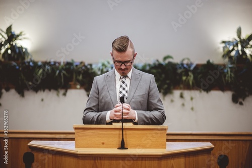 Male in a grey suit preaching words of the Holy Bible at the altar of a church photo