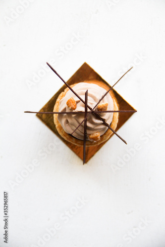 Wallpaper Mural Choux (profiteroles) with chocolate creme, salted caramel, and whipped ganache with milk chocolate, and chocolate decor. Choux is on a golden cardboard cake base, on a white background. Top view. Torontodigital.ca