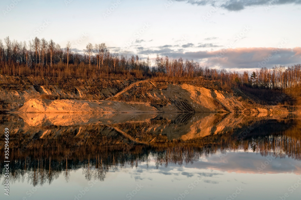 Mirror image in the lake of steep banks in spring. Vsevolozhsk. Leningrad region.