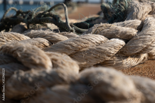 Old, strong mooring rope lying on the dock. Close up, shallow depth of field.